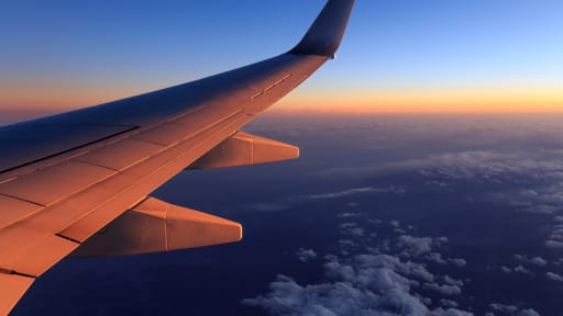 Blick aus dem Fenster eines Flugzeugs auf den Flügel im Sonnenuntergang