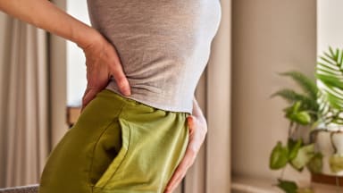 Frau hält sich Rücken und Beckenboden