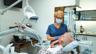 Eine Zahnärztin behandelt einen älteren Patienten