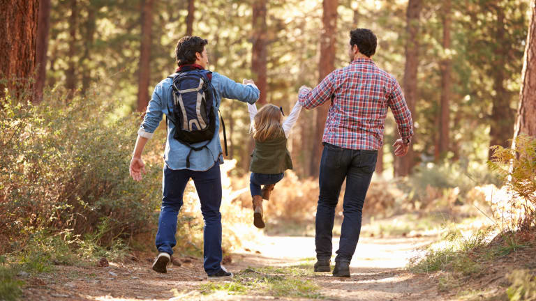 zwei Männer mit Kind spazieren im Wald