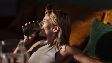 Entspannte Frau trinkt bei Hitze ein Glas Wasser