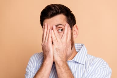 Mann verbirgt mit den Händen sein Gesicht