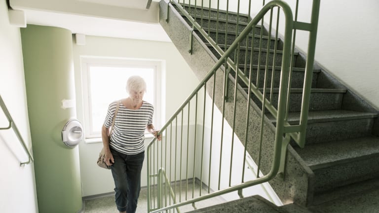 Ältere Frau steigt Treppen im Treppenhaus