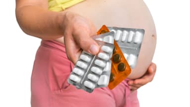 pregnant woman holding pills in one hand