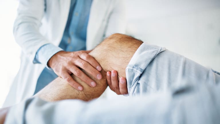 Arzt untersucht das Knie eines Patienten