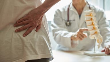 Patient mit Kreuzschmerzen fasst sich an den unteren Rücken 