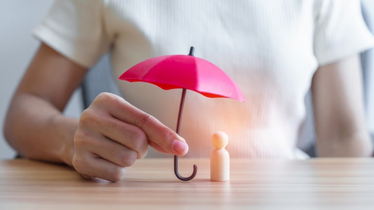 Regenschirm über Holzfigur zum Schutz