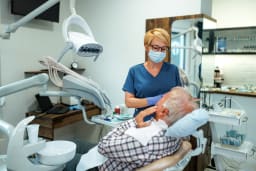 Eine Zahnärztin behandelt einen älteren Patienten