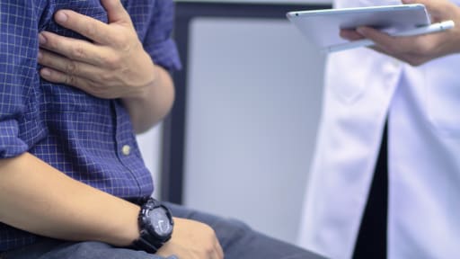 Patient fasst sich bei hausärztlicher Untersuchung an den schmerzenden Brustbereich