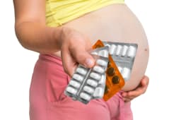 pregnant woman holding pills in one hand
