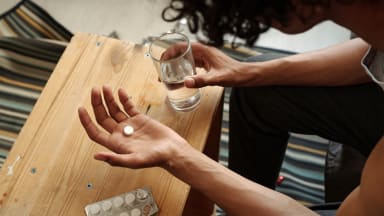 Mann hält Pille und Glas Wasser in der Hand
