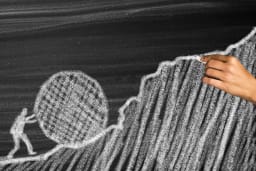 Teasrebild Person schiebt einen Ball den Berg hoch gettyimages-2227659951.jpg