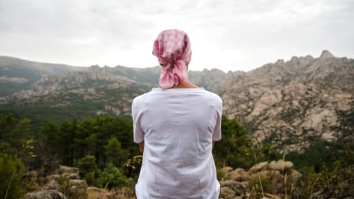 Eine Frau mit Kopftuch sitzt in einer Berglandschaft