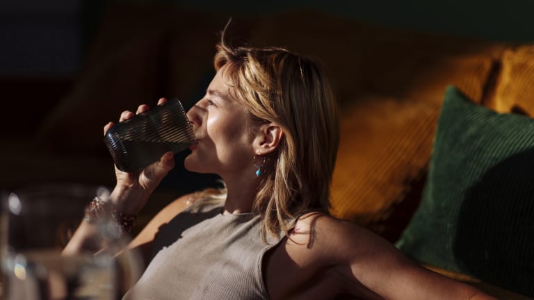 Entspannte Frau trinkt bei Hitze ein Glas Wasser