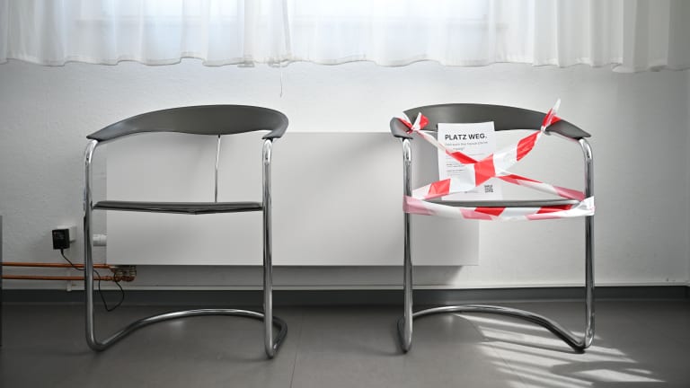 Blick auf einen abgesperrten Stuhl im Wartezimmer einer Hausarztpraxis in Stuttgart auf dem ein Schild mit der Aufschrift «Platz weg. Bald auch ihre hausärztliche Versorgung?» liegt. 
