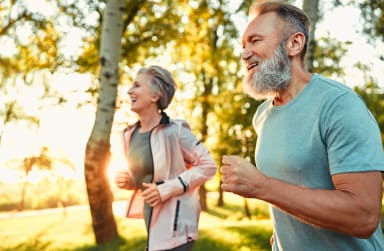 Ein eher älteres Ehepaar beim Joggen im sonnigen Park