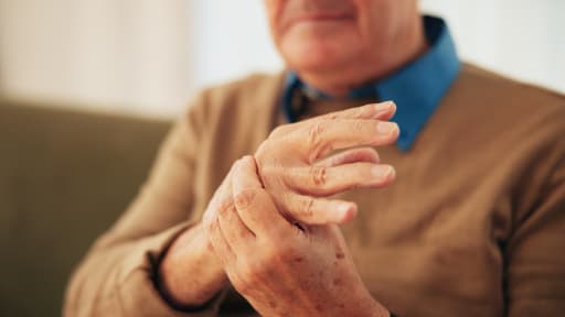 Älterer Mann fasst sich an seine schmerzende Hand