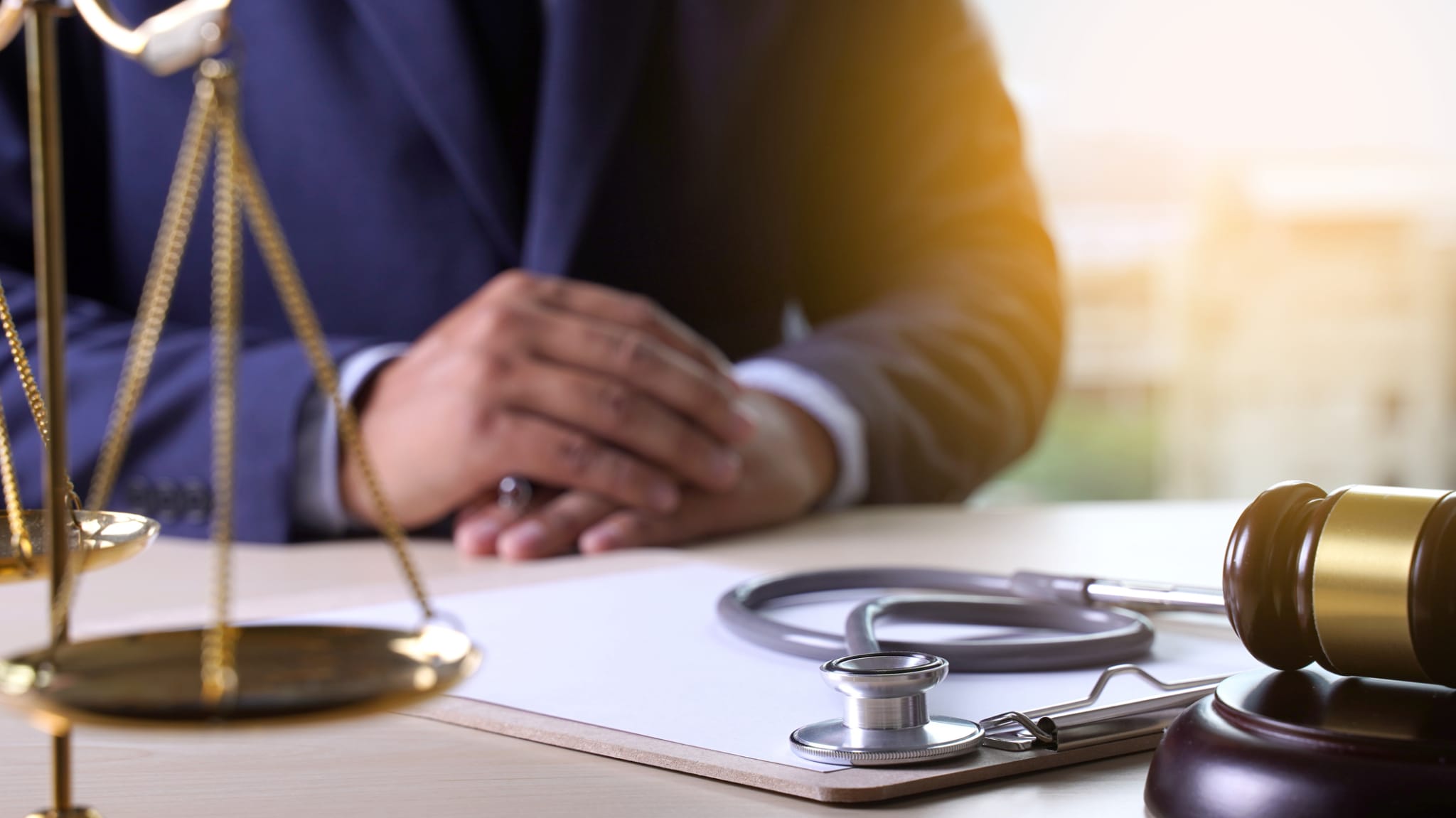 Stethoskop, Hammer und Waage am Anwaltstisch