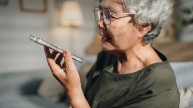 Seniorin nutzt eine KI-gestützte App auf ihrem Smartphone