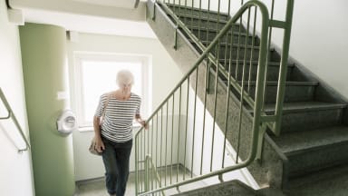 Ältere Frau steigt Treppen im Treppenhaus