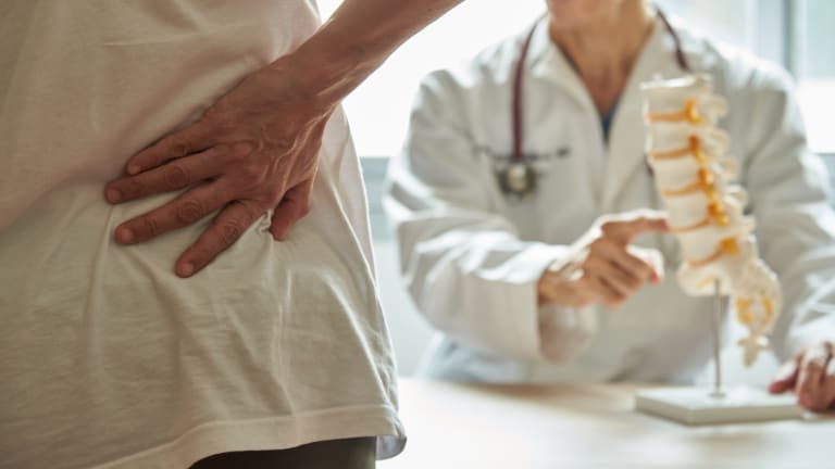 Patient mit Kreuzschmerzen fasst sich an den unteren Rücken 