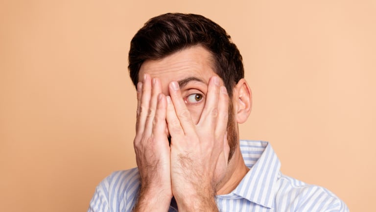 Mann verbirgt mit den Händen sein Gesicht