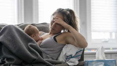 Erschöpfte junge Frau mit Baby auf dem Bauch