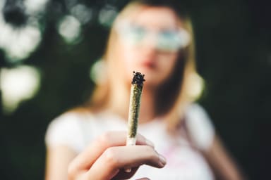Junge Frau hält Marihuana-Joint in der Hand